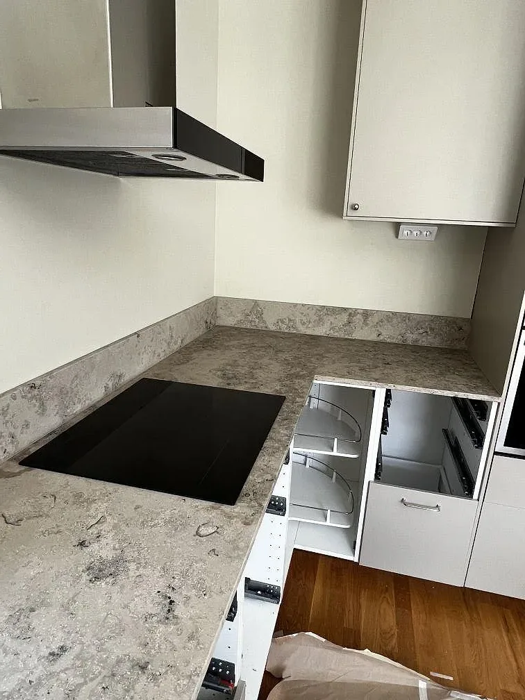 Matt Jura Grey köksbänkskiva med svart induktionshäll, uppvikt stänkkant och vita köksstommar i Ytterby.