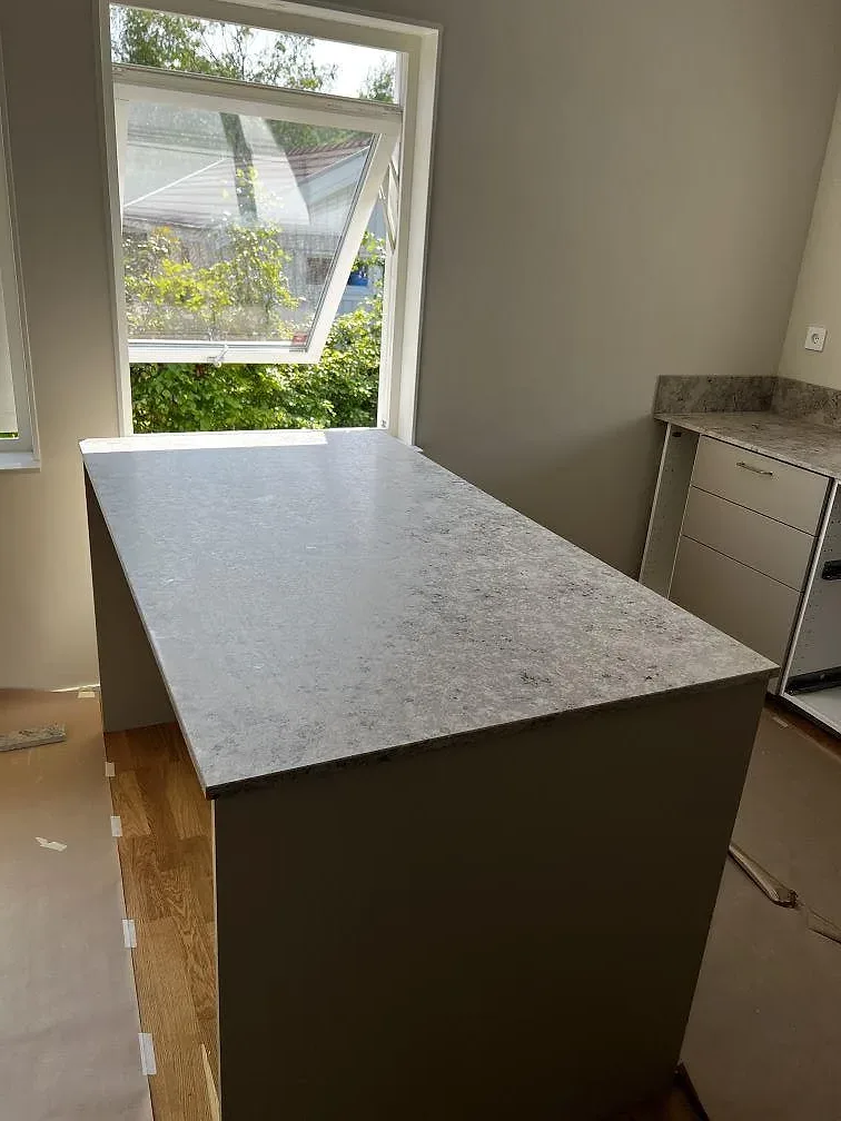 Halvö med matt Jura Grey kalksten och synlig stenstruktur framför stora fönster i ett kök i Ytterby.