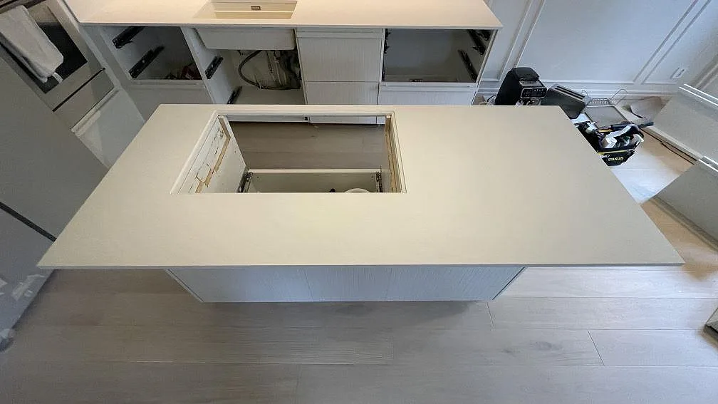 Köksö i Laminam Bianco Spacco med stort öppet urtag, monterad som ljus keramisk arbetsyta i Malmö.