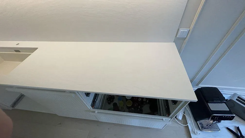 Ljus köksö och arbetsyta i Laminam Bianco Spacco, strukturerad keramik, fotograferad ovanifrån under montering i Malmö.