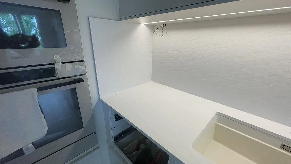 Väggbänk i Laminam Bianco Spacco, ljus keramik, med synlig diskho och väggskiva bakom bänken i ett kök i Malmö.