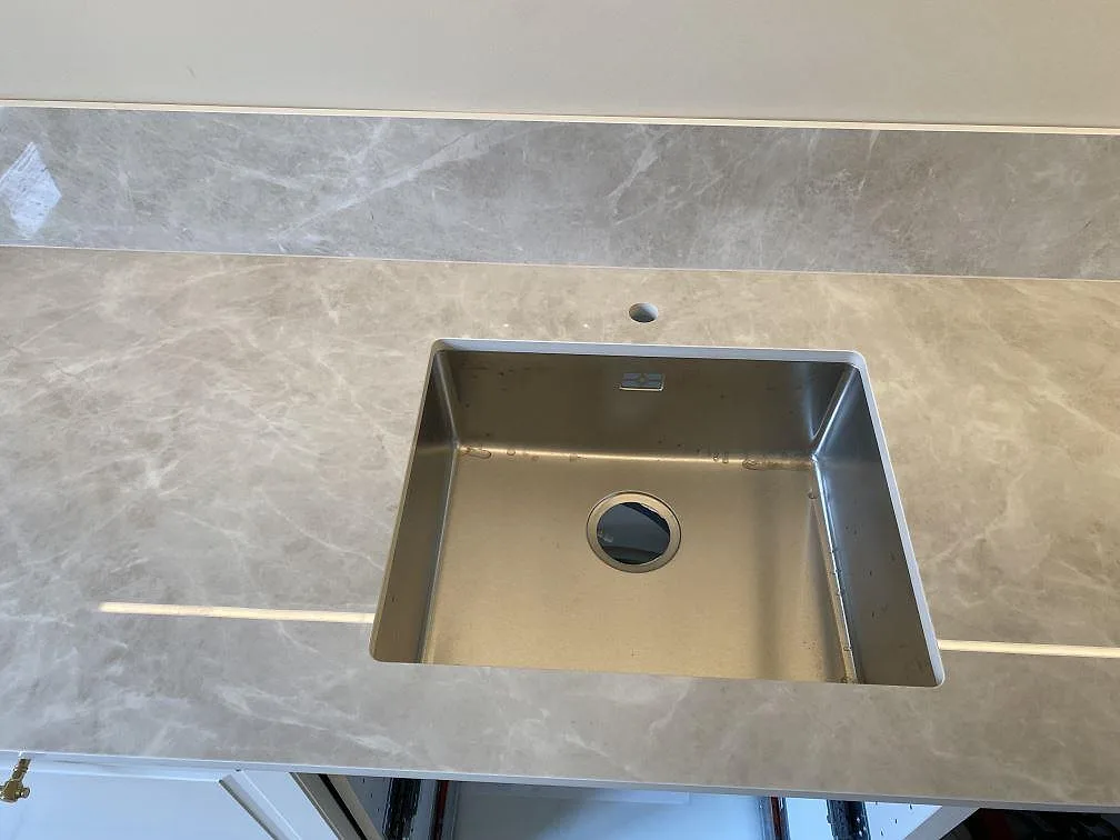 Detalj av diskho i polerad Laminam Diamond Cream keramisk bänkskiva med blank ådring och låg stänkkant i Malmö.