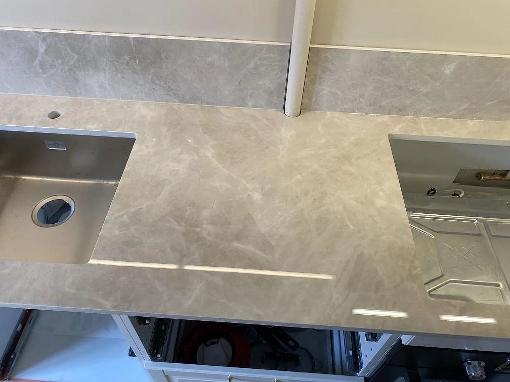 Polerad Laminam Diamond Cream bänkskiva i keramik mellan diskho och spisplats, med ljus ådring i ett kök i Malmö.