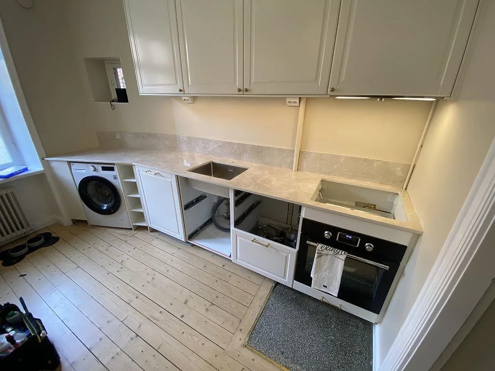 Köksbänkskiva i polerad Laminam Diamond Cream keramik med låg stänkkant, diskho och spiszon i ett kök i Malmö.