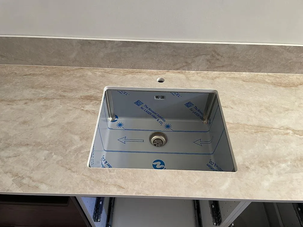 Diskhoområde i polerad Makrana keramik med blandarhål och låg stänkkant i ett kök i Borås.