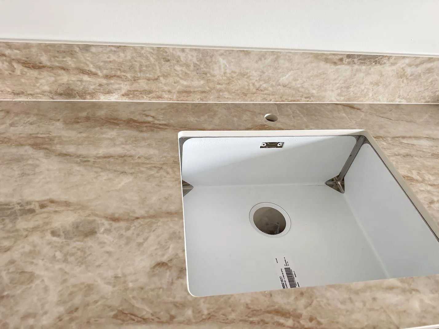 Detalj av polerad Makrana keramik runt hoöppning och rund öppning för blandare, med matchande låg stänkkant i ett kök i Jönköping.