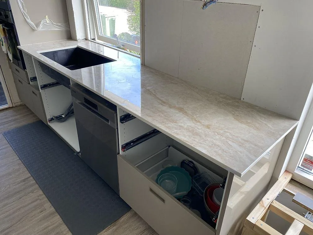 Polerad Makrana som köksbänk vid fönster i Kävlinge, med stänkkant och ljus beigegrå ådring under montering.