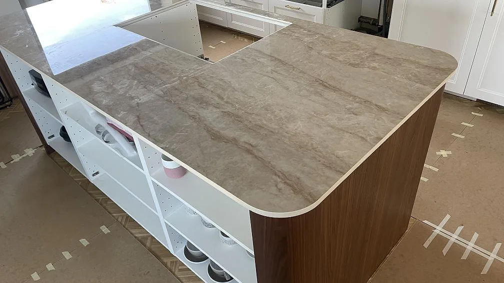 Stor köksö i polerad Makrana keramik med rundat hörn, ljus kant och ådrad yta över öppna köksstommar i Kongens Lyngby.