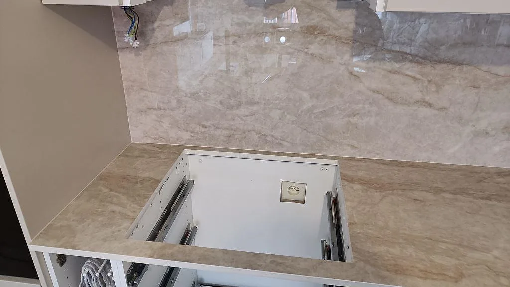 Närbild av polerad Makrana keramik på köksbänk och hög väggbeklädnad under montering i Malmö.