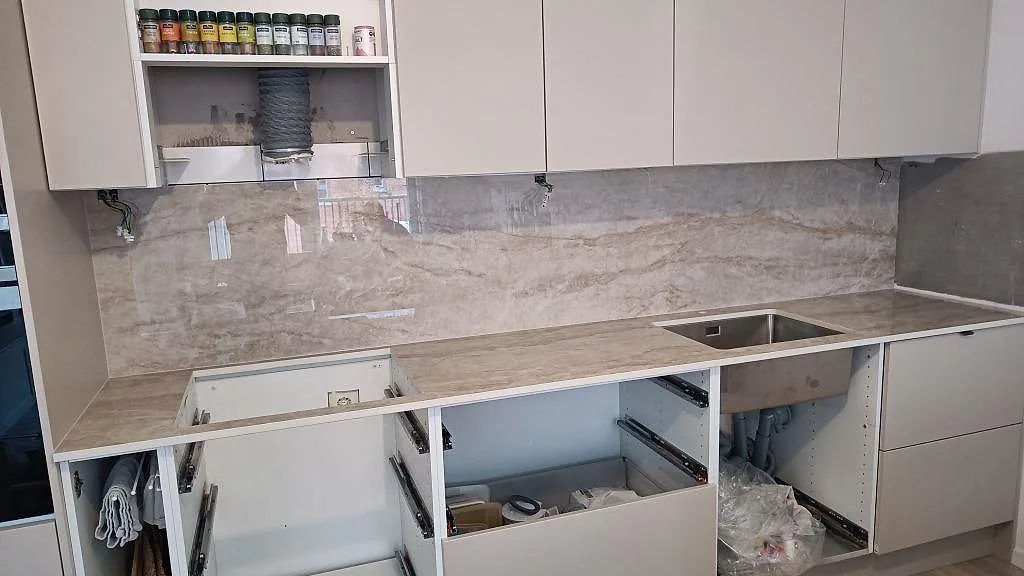 Köksbänkskiva i Makrana keramik, polerad, med matchande väggbeklädnad i ett kök under montering i Malmö.