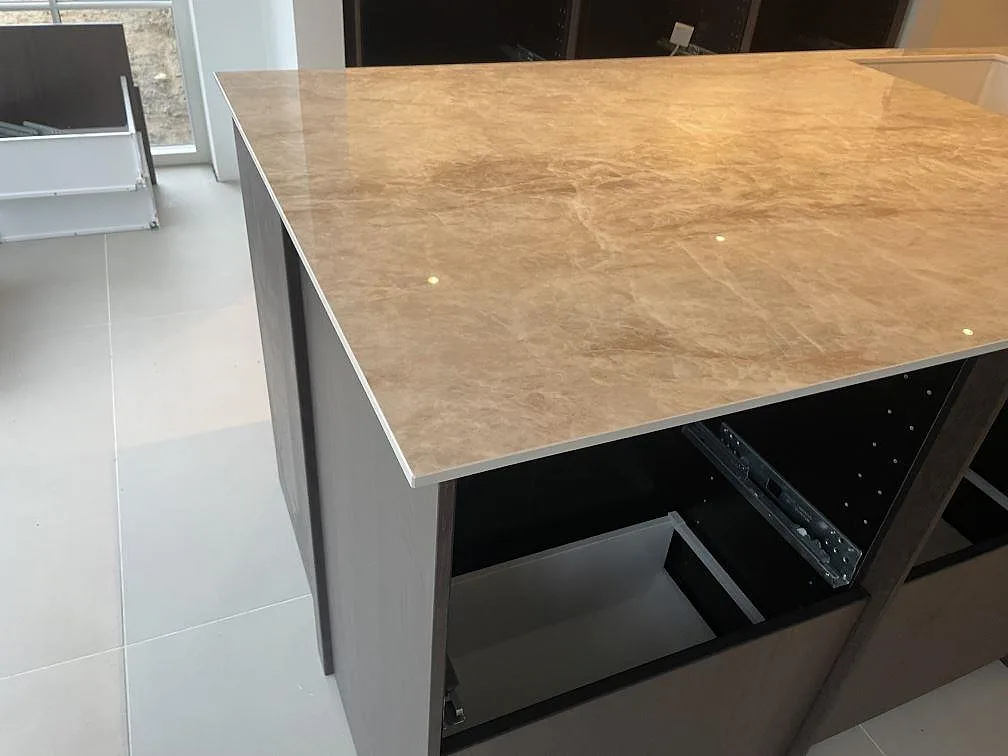 Detalj av blank polerad Makrana keramik med ljus ådring och tunn kant på köksö i Middelfart.