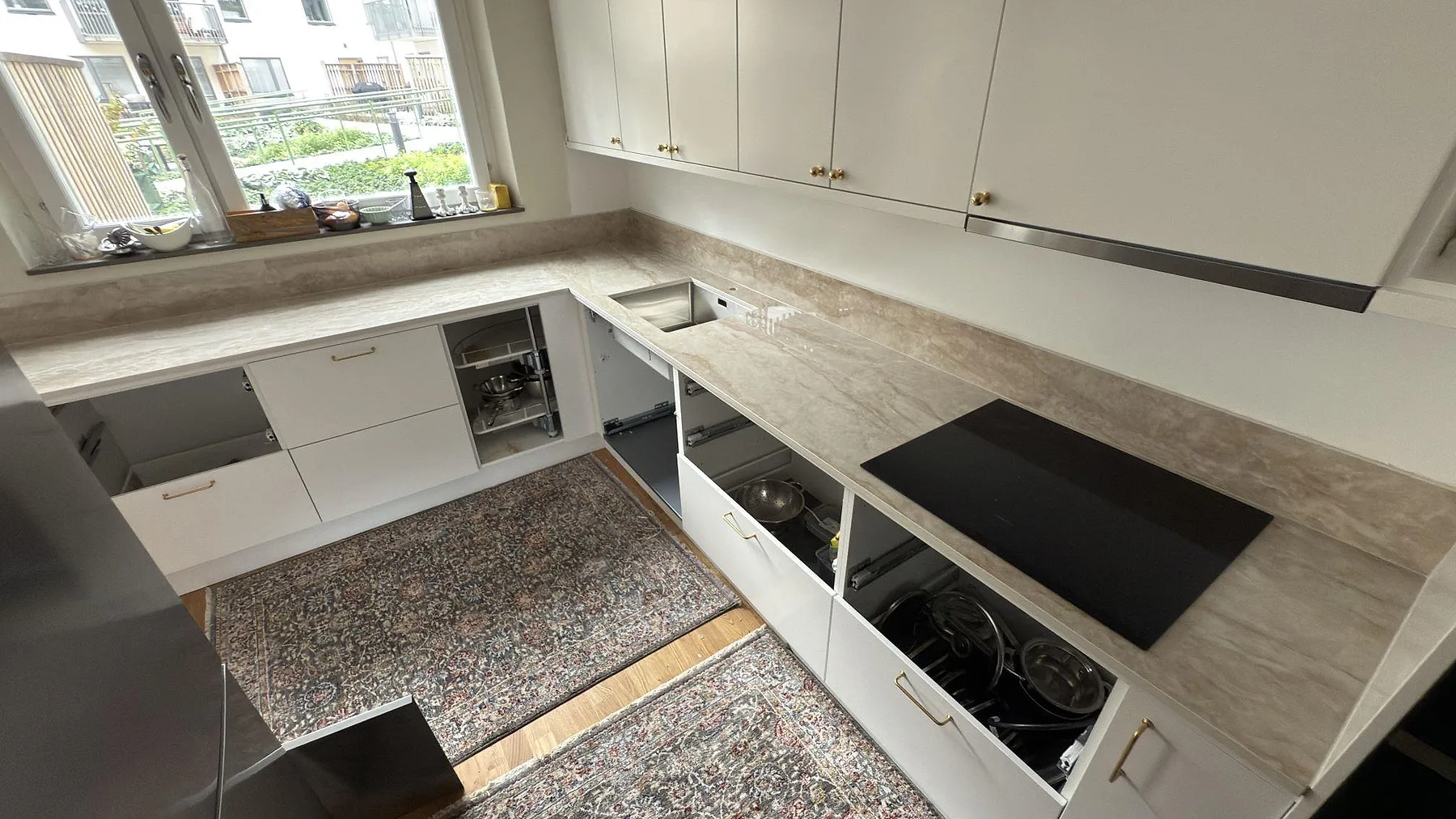 Polerad köksbänkskiva i keramiken Makrana med rostfri diskho, svart häll och matchande stänkskydd i ett kök i Solna.