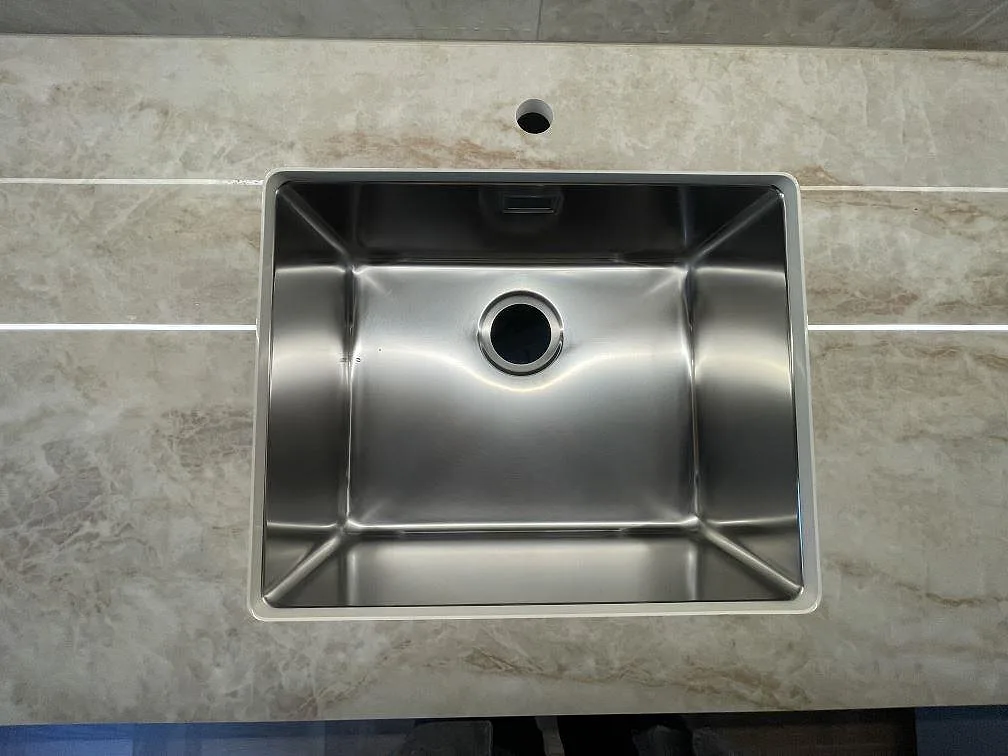 Underlimmad rostfri diskho i polerad Makrana keramikbaenkskiva med kranhaal i ett koek i Uppsala.