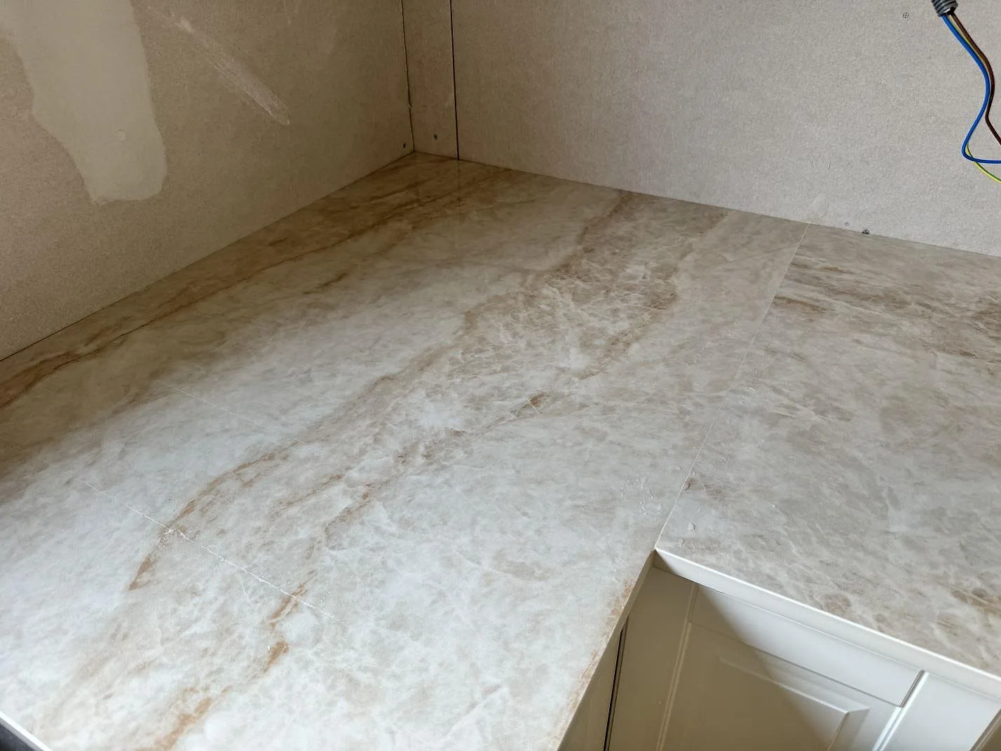 Närbild på hörn i köksbänkskiva av polerad Makrana keramik med mjuk beige ådring i Vinslöv.