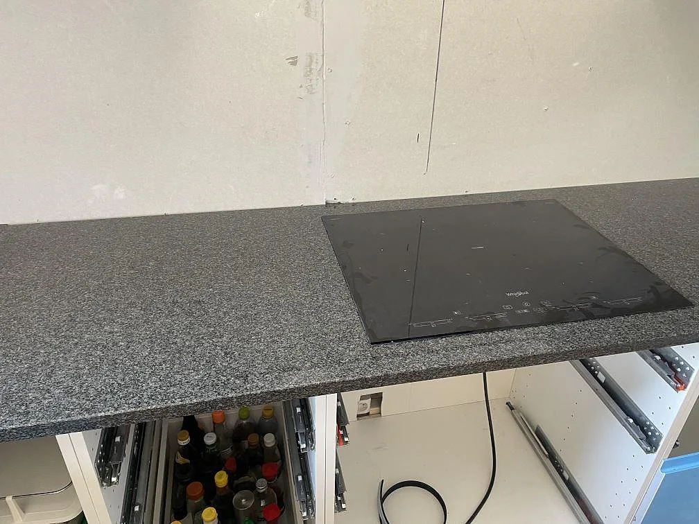 Köksbänkskiva i Nero Africa granit i Bjuv med infälld induktionshäll från Whirlpool, fotad under montering.