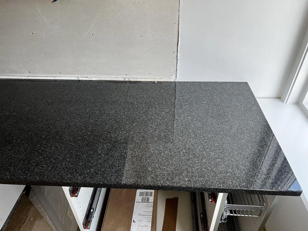 Blank polerad Nero Africa granitbänkskiva vid fönster och vägg i ett kök i Floda.