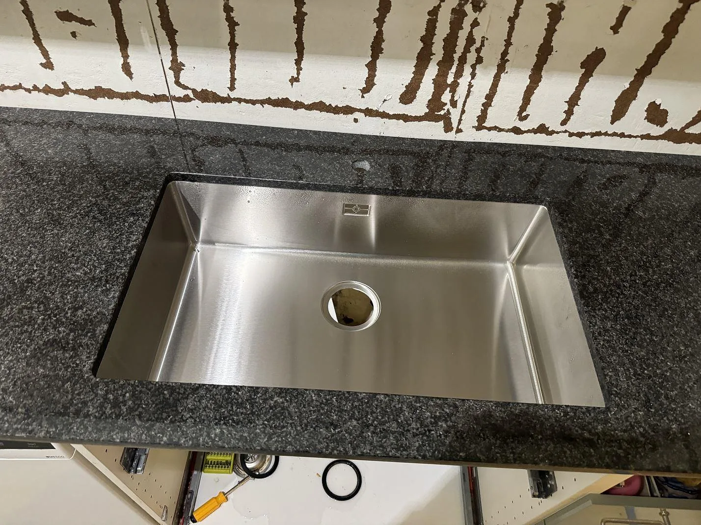 Detalj av rostfri diskho i polerad Nero Africa granit med blank stenyta i köket i Floda.