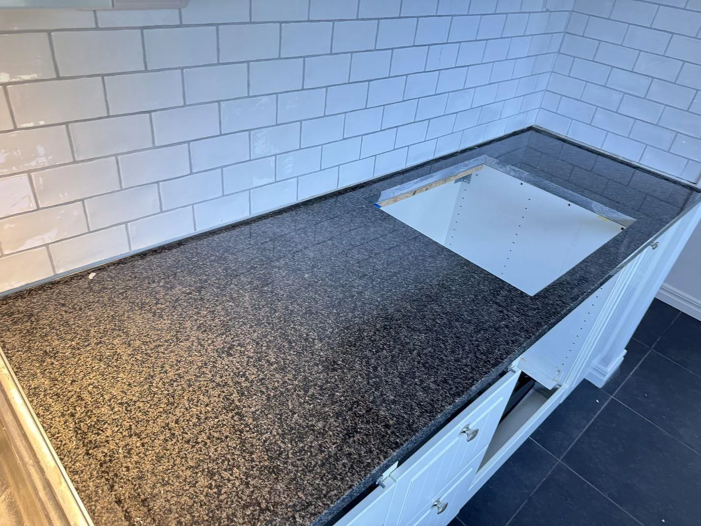 Lång köksbänkskiva i polerad Nero Africa granit med öppet urtag under montering i ett kök i Göteborg.
