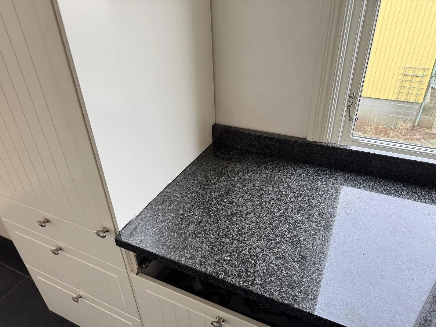 Fönstersida med polerad Nero Africa granit, uppvikt kant och vita köksluckor i Göteborg.