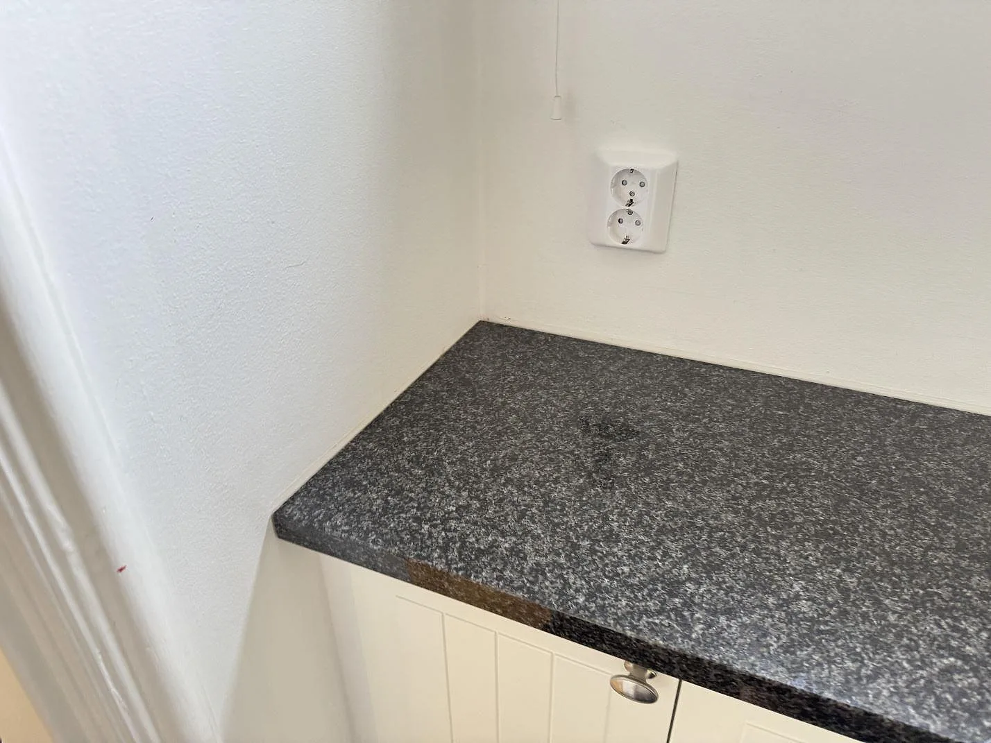 Hörnmonterad köksbänkskiva i polerad Nero Africa granit mot vita väggar i Göteborg.
