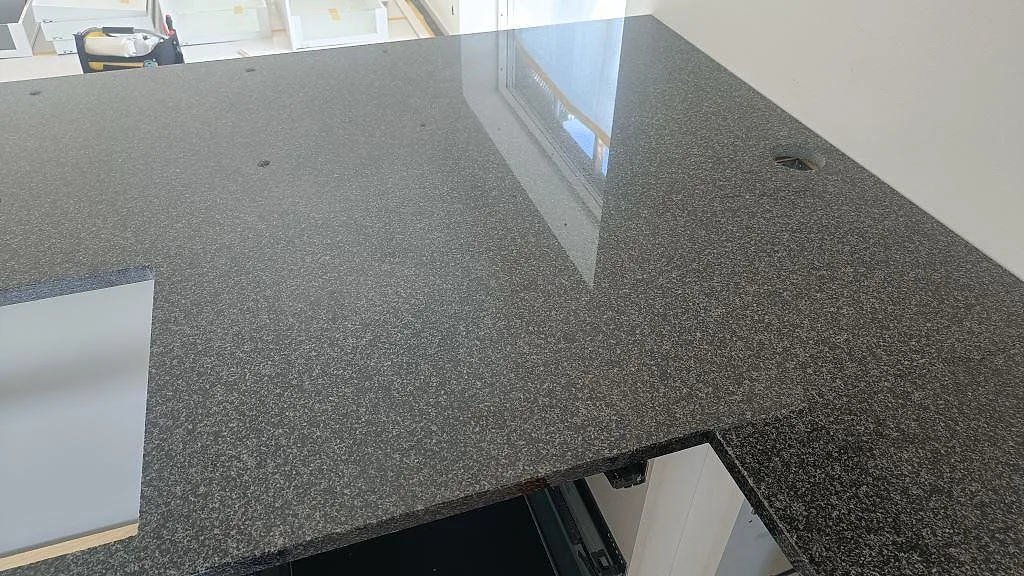 Bänkskiva i polerad Nero Africa granit med öppningar och reflektion från stort fönster i Halmstad.