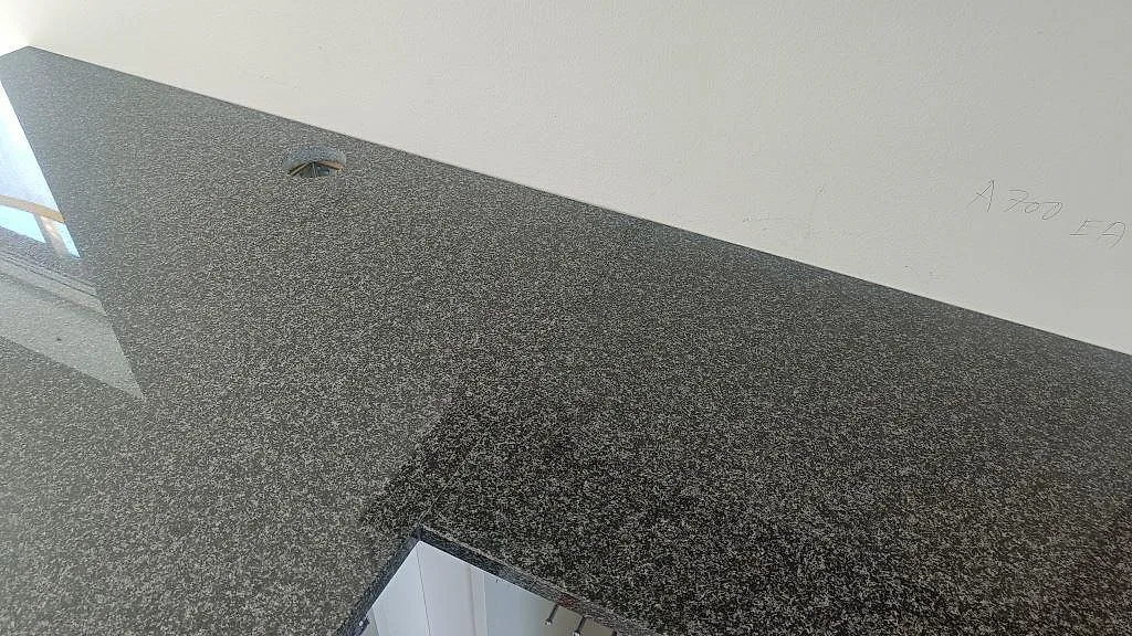 Väggbänk i polerad Nero Africa granit med rund öppning och mörk stenstruktur i kök i Halmstad.