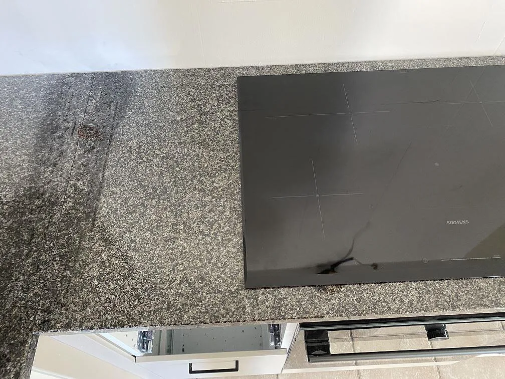 Detalj av häll och arbetsyta i polerad Nero Africa granit på köksbänkskiva i Hjärnarp.