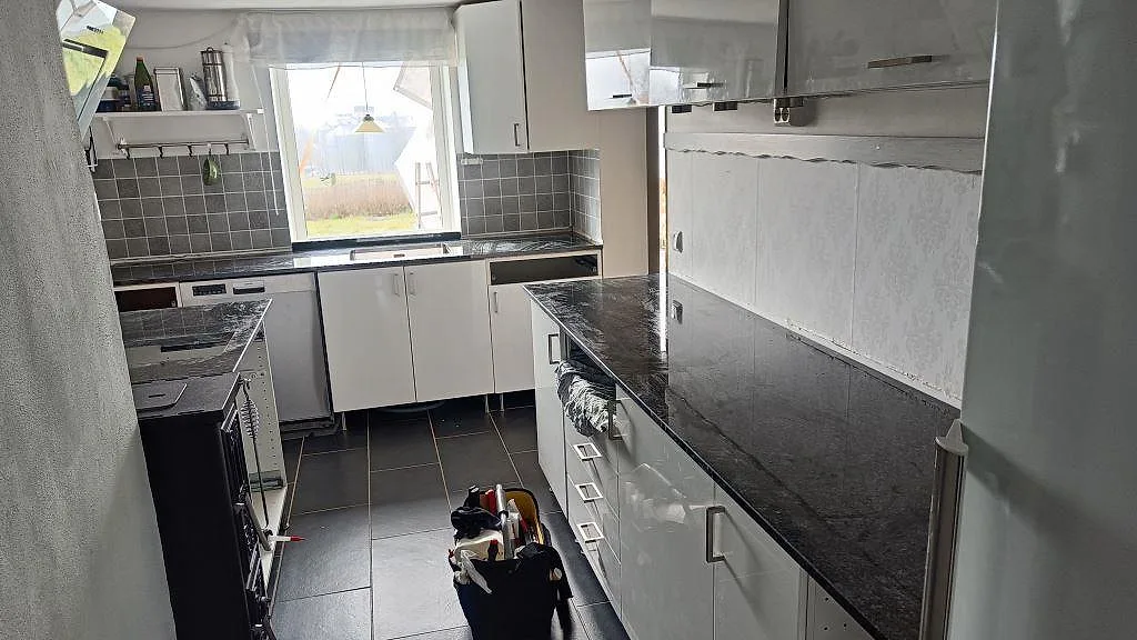 Köksbänkskiva i mörk granit Nero Africa, polerad, installerad på båda sidor i ett galleykök under montering i Kävlinge.