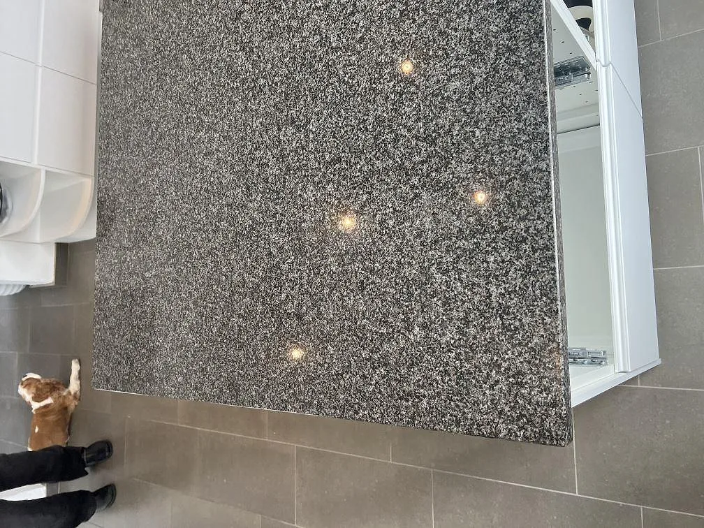 Polerad Nero Africa granit på installerad köksbänkskiva med synlig stenstruktur och vita köksstommar i Klagshamn.