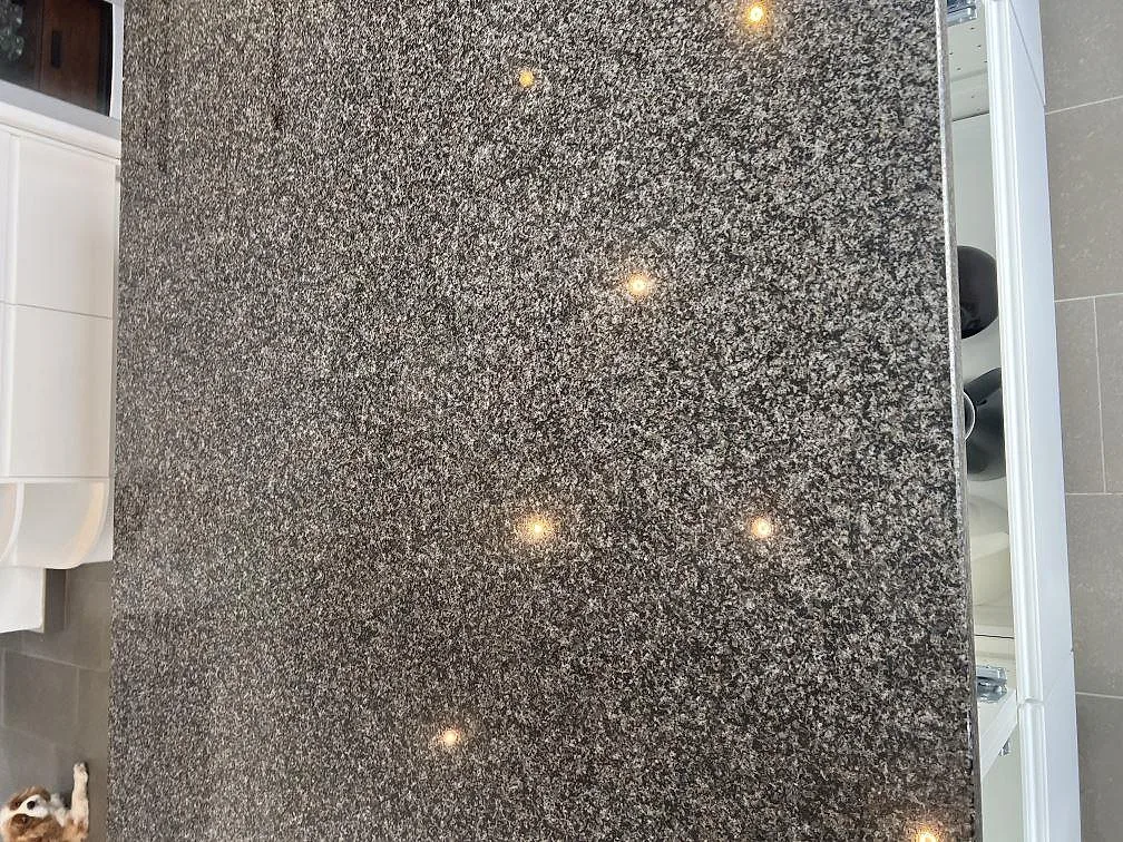 Detaljbild av gråspräcklig Nero Africa granit, polerad köksbänkskiva med ljusreflexer i Klagshamn.