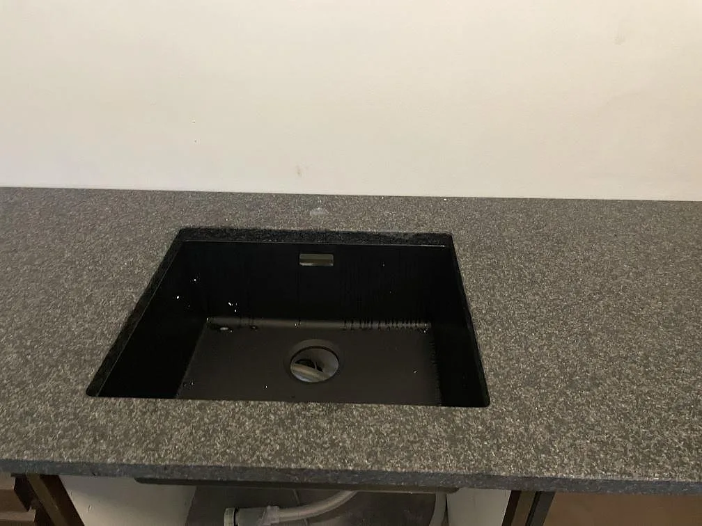 Underlimmad svart diskho i en matt Nero Africa granitbänkskiva i ett kök i Köbenhavn.