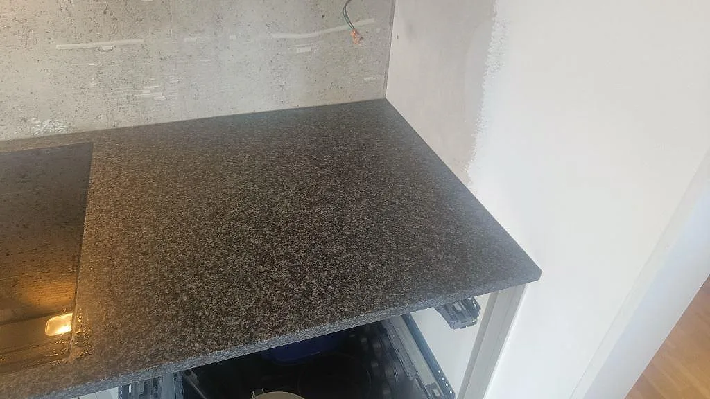 Närbild på matt Nero Africa granit bredvid svart häll, monterad som köksbänkskiva i Lomma.