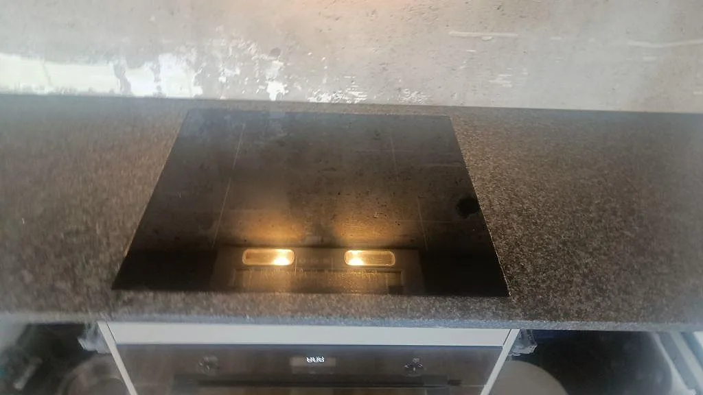 Svart häll i en gråspräcklig köksbänkskiva av matt Nero Africa granit under montering i Lomma.