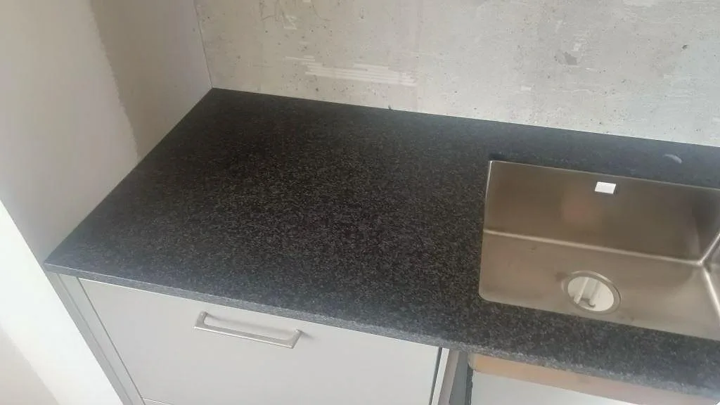 Matt Nero Africa granit vid diskzonen med rostfri underlimmad diskho och vit kökslucka i ett kök i Lomma.
