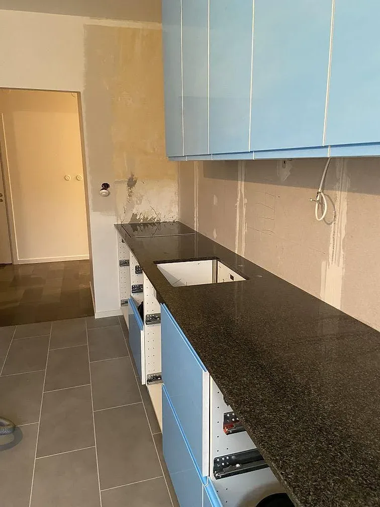 Mörk Nero Africa-granitbänkskiva med köksö och köksblandare under montering i ett kök i Malmö.