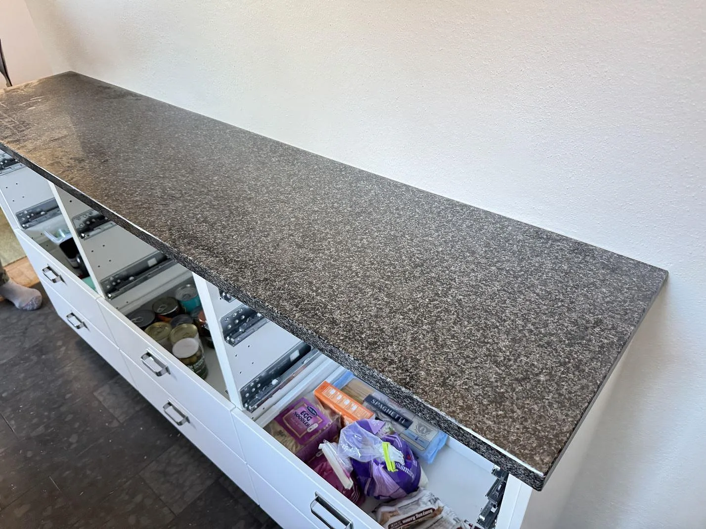 Rak köksbänkskiva i polerad Nero Africa granit med mörk kornig yta på vita lådor i Malmö.