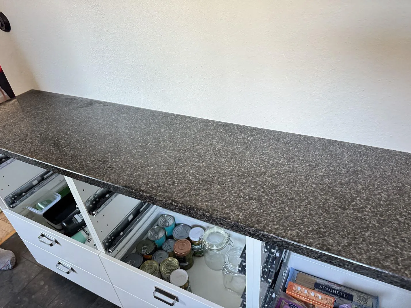 Detalj av polerad Nero Africa granit som köksbänkskiva över öppna köksstommar i Malmö.