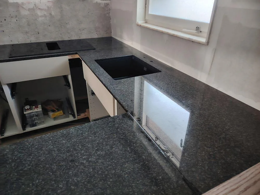 Närbild av Nero Africa granit i polerad finish med diskhoöppning och blank stenyta i ett kök i Nacka.