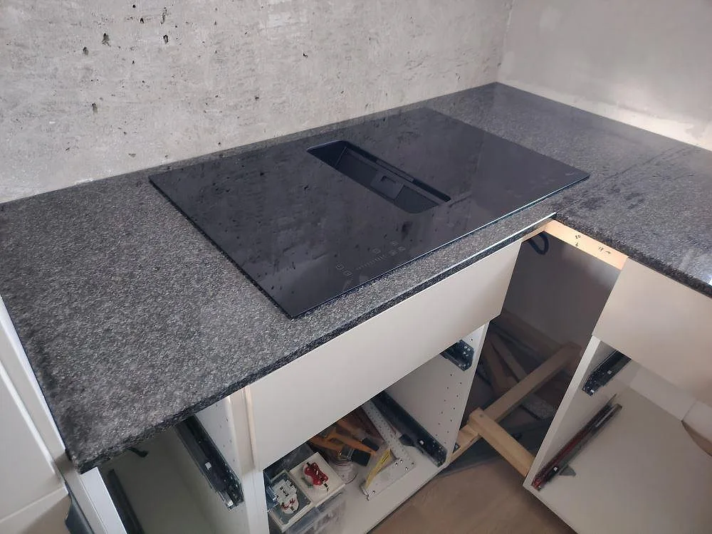 Häll monterad i polerad Nero Africa granit, 20 mm, i ett kök under montering i Nacka.