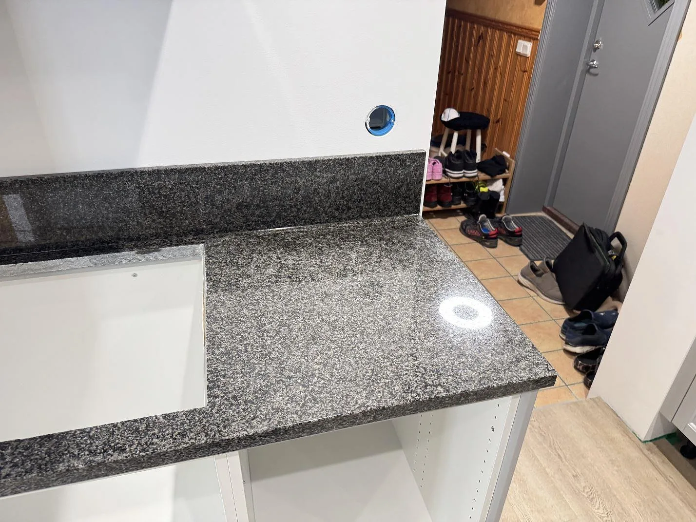 Polerad Nero Africa granit med blank reflektion, lågt stänkskydd och öppna underskåp i ett kök i Rydsgård.