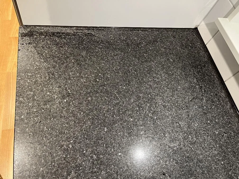 Närbild ovanifrån på den finkorniga ytan hos en polerad Nero Africa-granitbänkskiva i ett kök i Skärhamn.