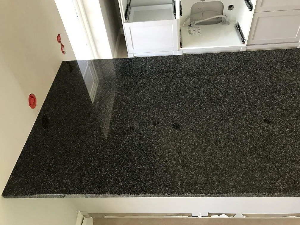 Polerad köksbänkskiva i svart Nero Africa-granit installerad mot vägg i ett kök i Torekov.