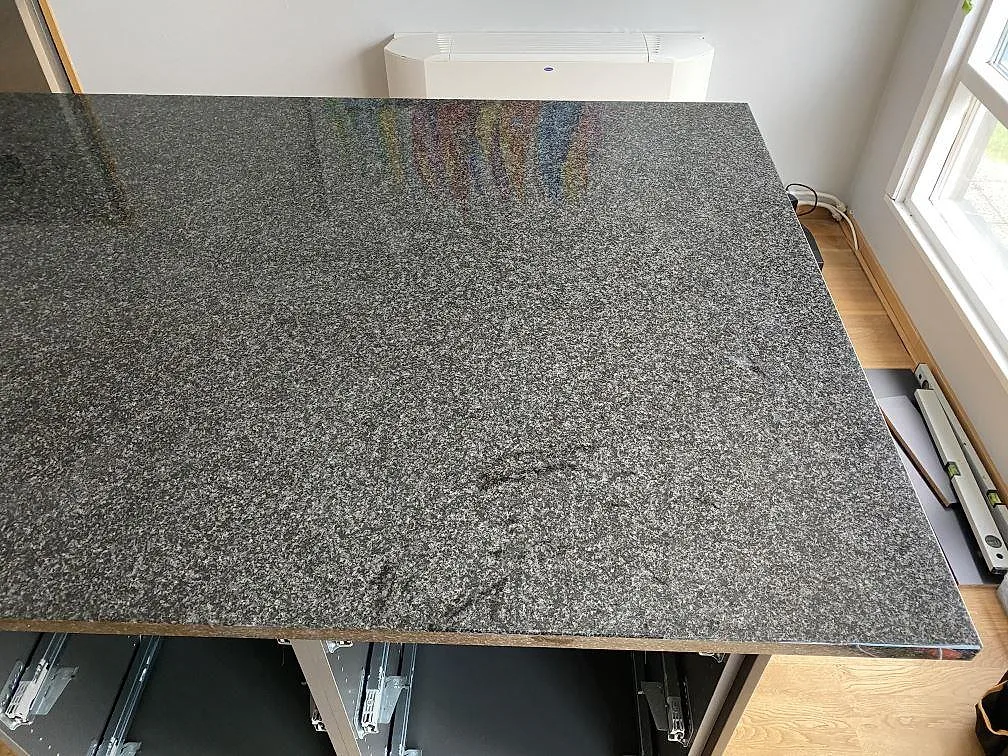 Polerad köksbänkskiva i Nero Africa granit med kornig spräcklig stenyta, sedd ovanifrån i ett kök under montering i Torslanda.