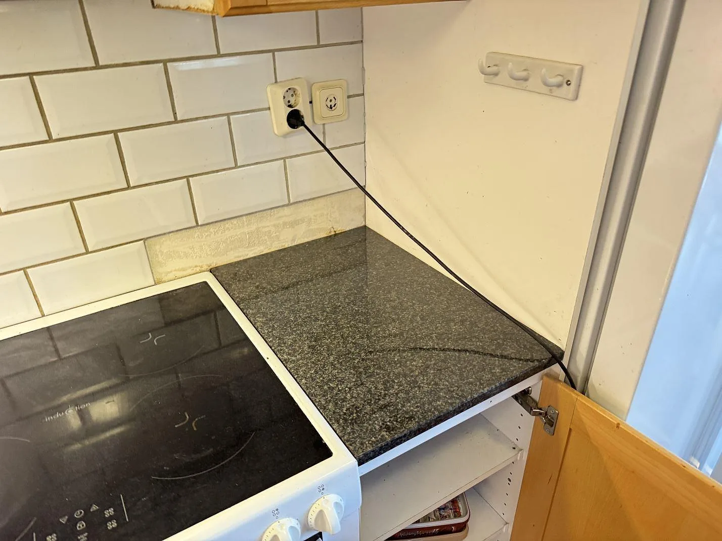 Sidobänk i polerad Nero Africa granit intill fristående spis och öppet träskåp i ett kök i Torslanda.