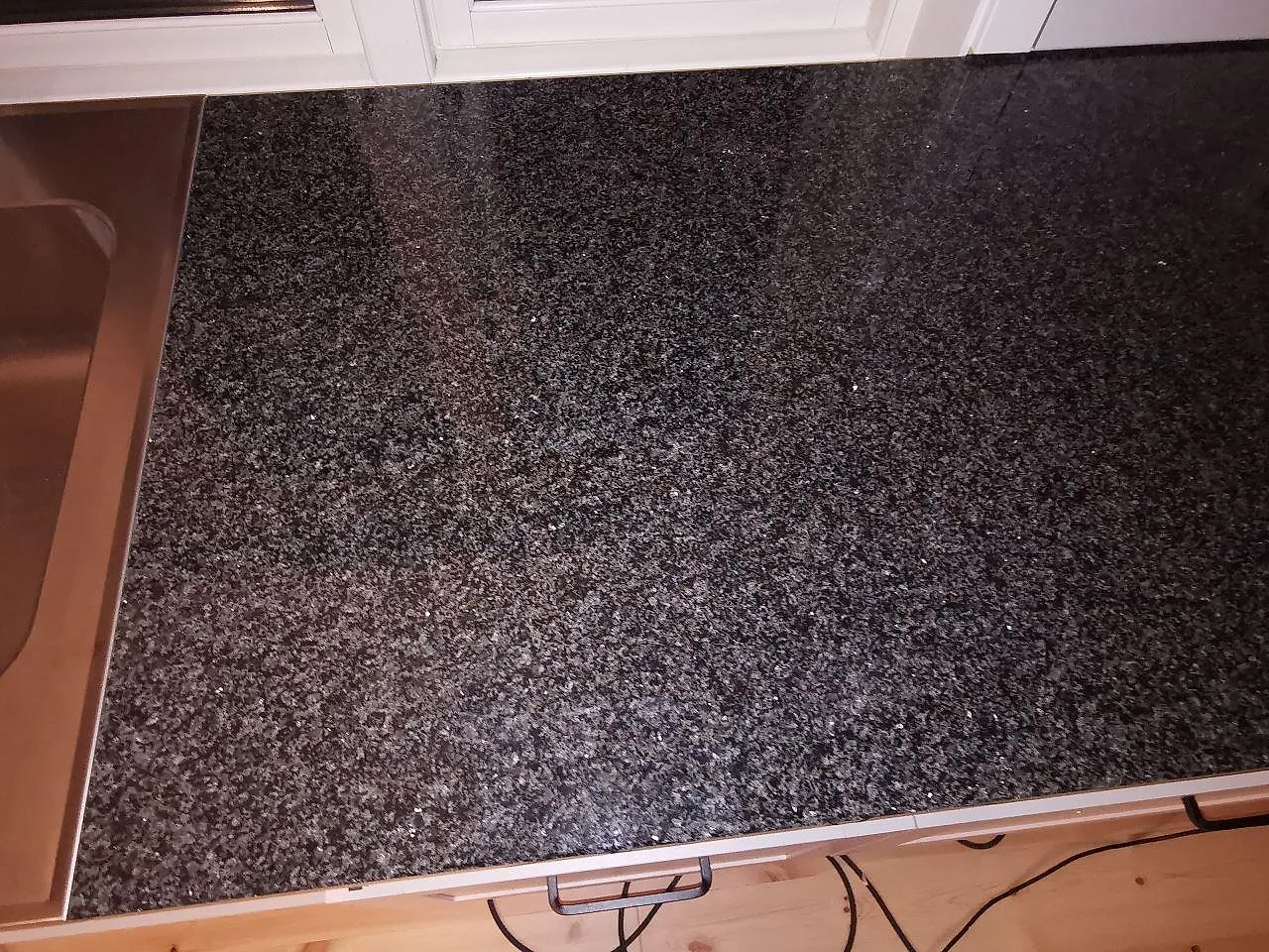 Installerad bänkskiva i Nero Africa granit, polerad mörk sten med rakfasad kant, i ett kök i Vaggeryd.