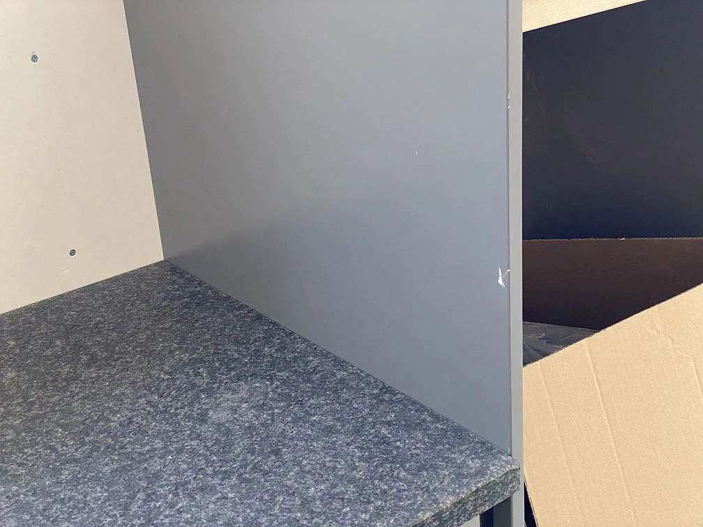 Hörnvy av matt Nero Africa granit mot grå sidopanel i ett kök under montering i Vilshärad.