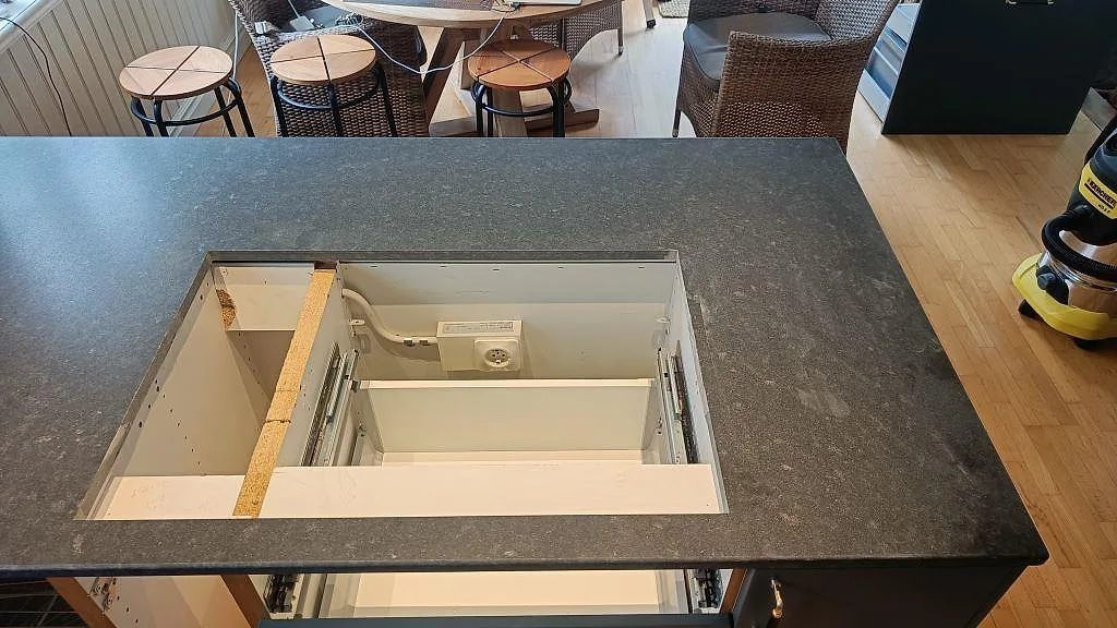 Köksö i matt Nero Assoluto granit sedd uppifrån, med urtag för lådhurts, i ett kök i Ängelholm.