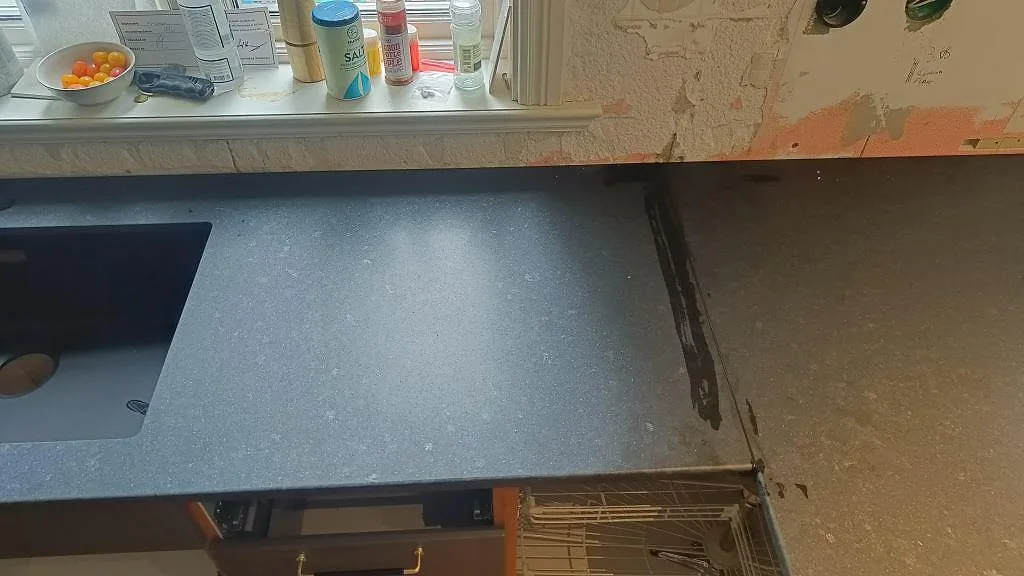Köksbänk i matt svart granit Nero Assoluto med underlimmad diskho under fönstret i ett kök i Ängelholm.