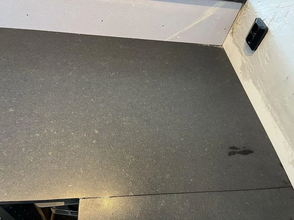 Köksbänkskiva i matt svart Nero Assoluto-granit med urfräsning för häll i ett kök i Ängelholm.