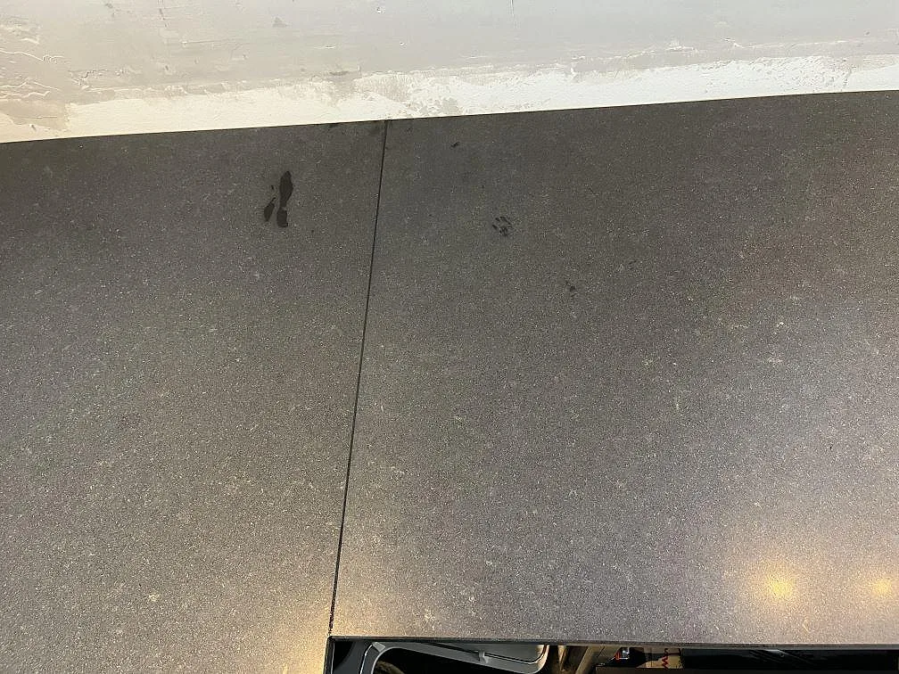 Matt svart Nero Assoluto-granitbänkskiva längs väggen i ett kök under montering i Ängelholm.